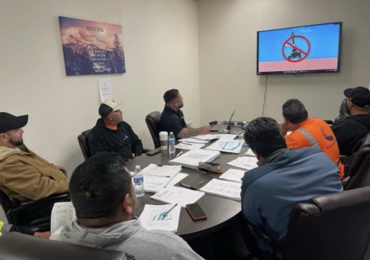Crew members in a classroom safety training session watching an equipment-hazard slide